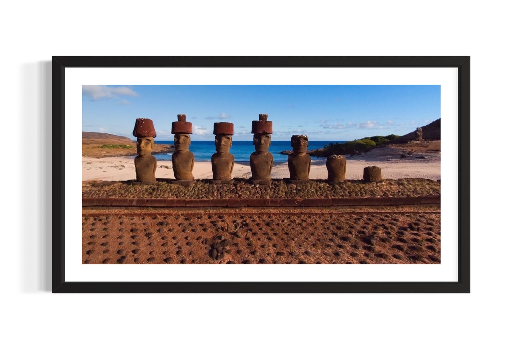 Framed photograph of stone Moai statues on an Easter Island beach with ocean and sky in the background.