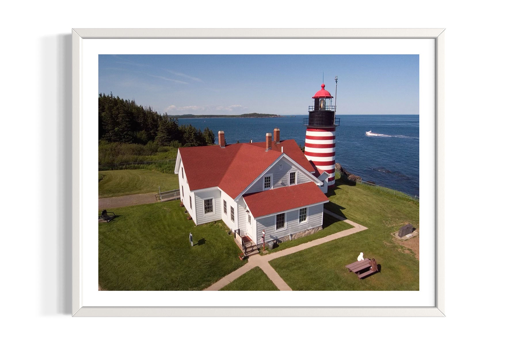Aerial photo of West Quoddy Lighthouse with a red roof and white stripes on a grassy area near water in Lubec, Maine by Evan Reinheimer.