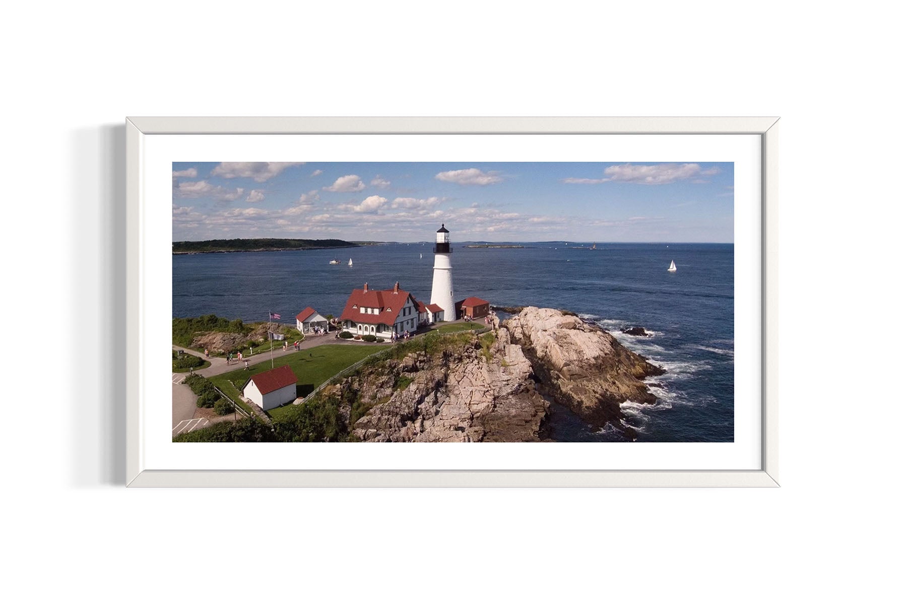 Framed aerial photograph of the Portland Head Light lighthouse on a rocky island with ocean and sky in the background by Evan Reinheimer.