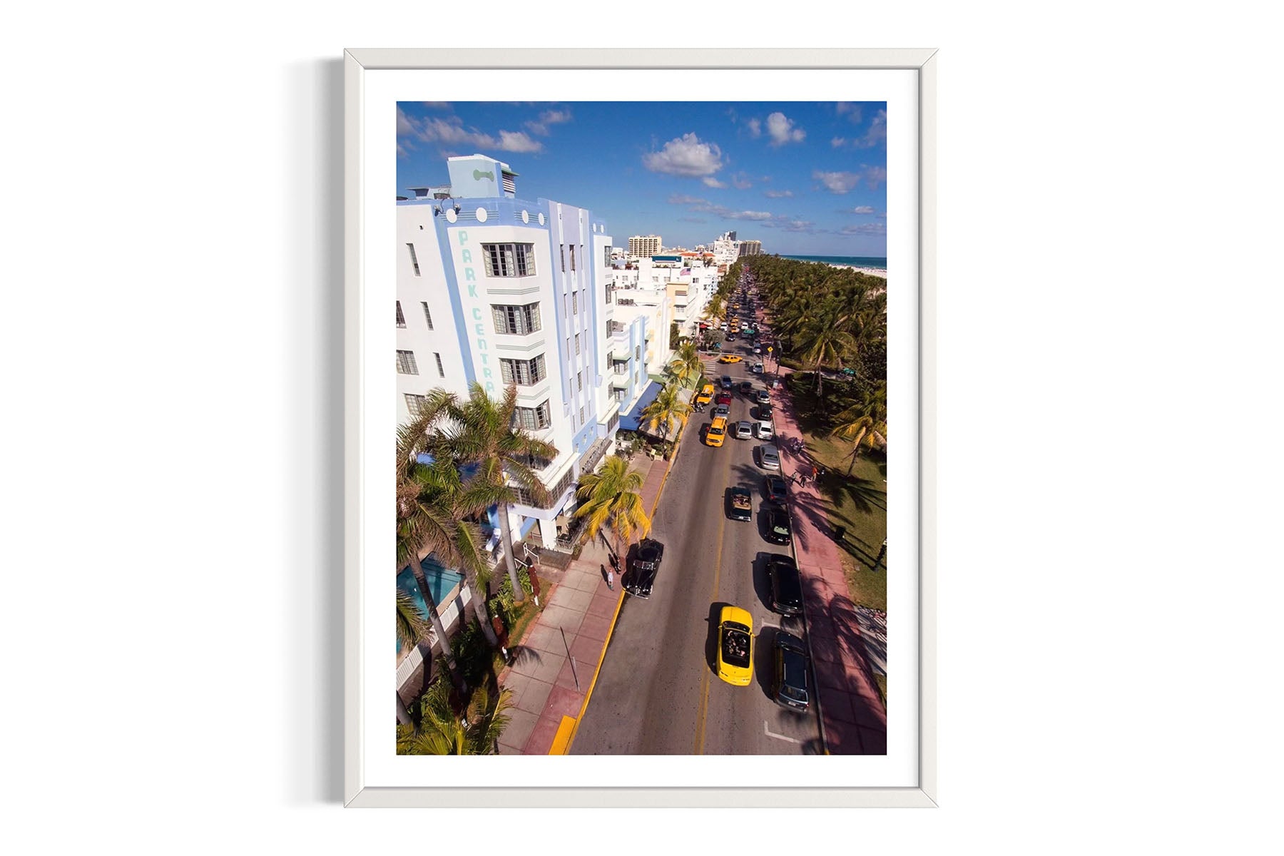 Framed aerial photograph of Ocean Drive in Miami Beach, FL with buildings, cars, and palm trees by Evan Reinheimer.