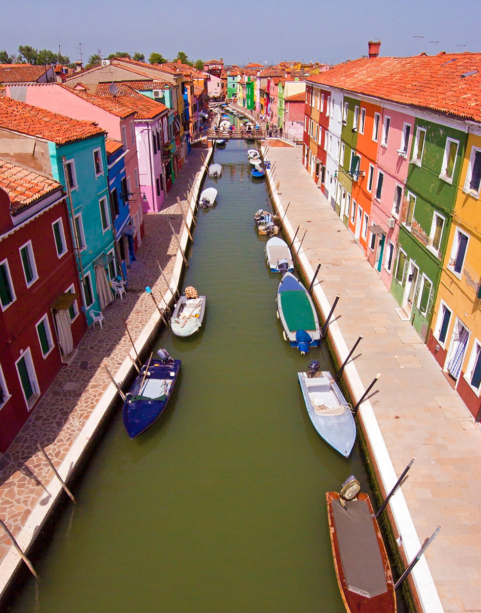 Aerial photograph of a colorful canal scene with boats in Burano, Venice, Italy by Evan Reinheimer.