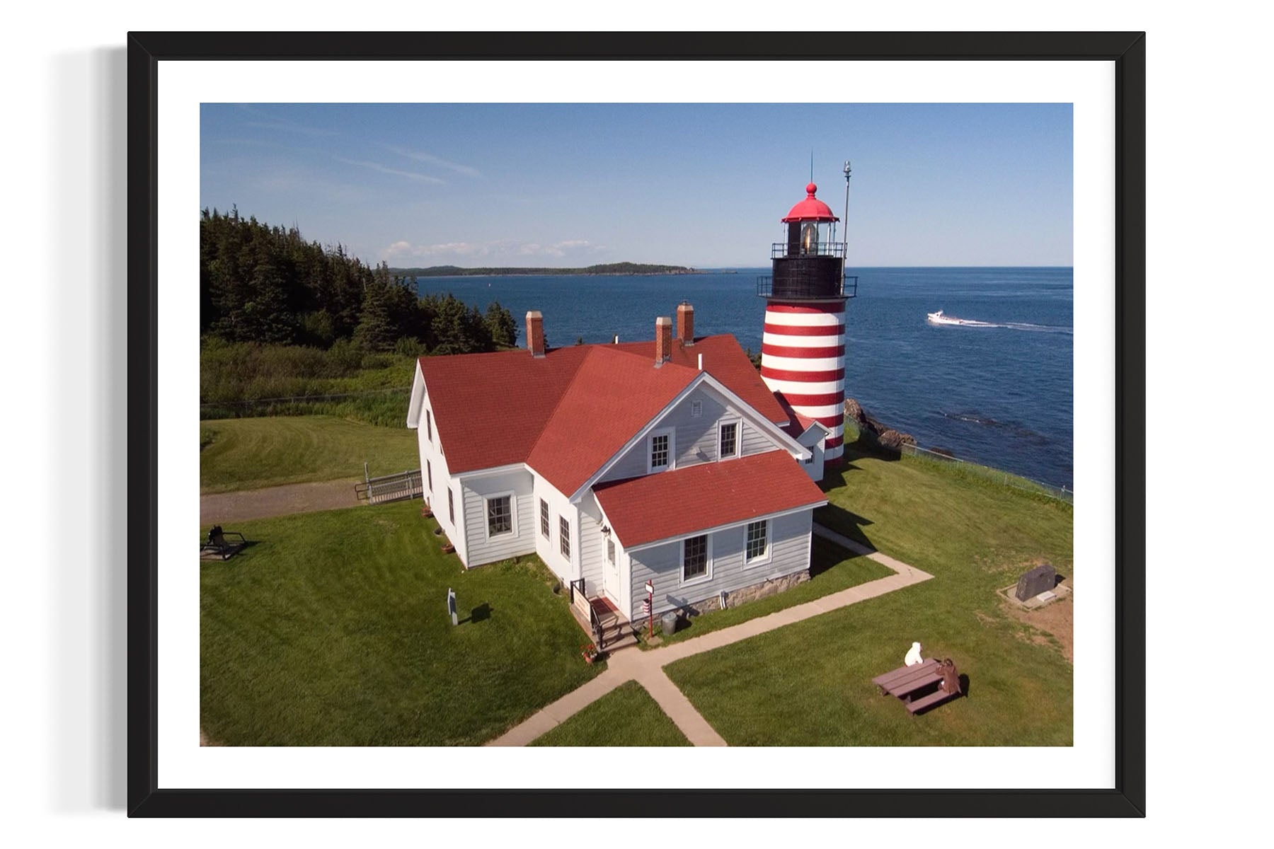 Aerial photo of West Quoddy Lighthouse with a red roof and white stripes on a grassy area near water in Lubec, Maine by Evan Reinheimer.