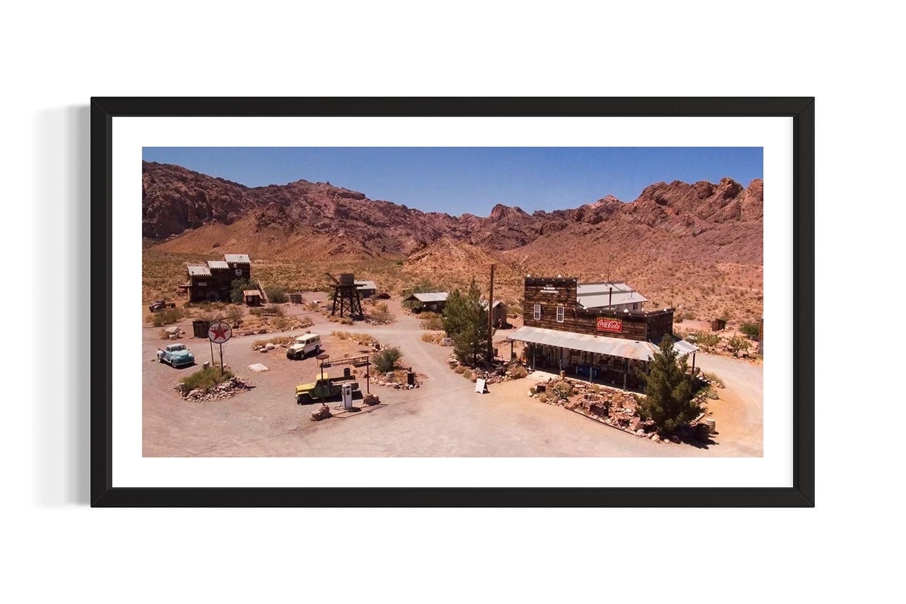 Aerial photograph of a desert landscape with buildings and vehicles in Nelson, Nevada, framed in black by Evan Reinheimer.