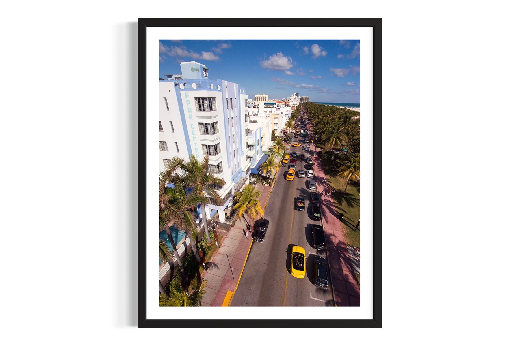 Framed aerial photograph of Ocean Drive in Miami Beach, FL with buildings, cars, and palm trees by Evan Reinheimer.