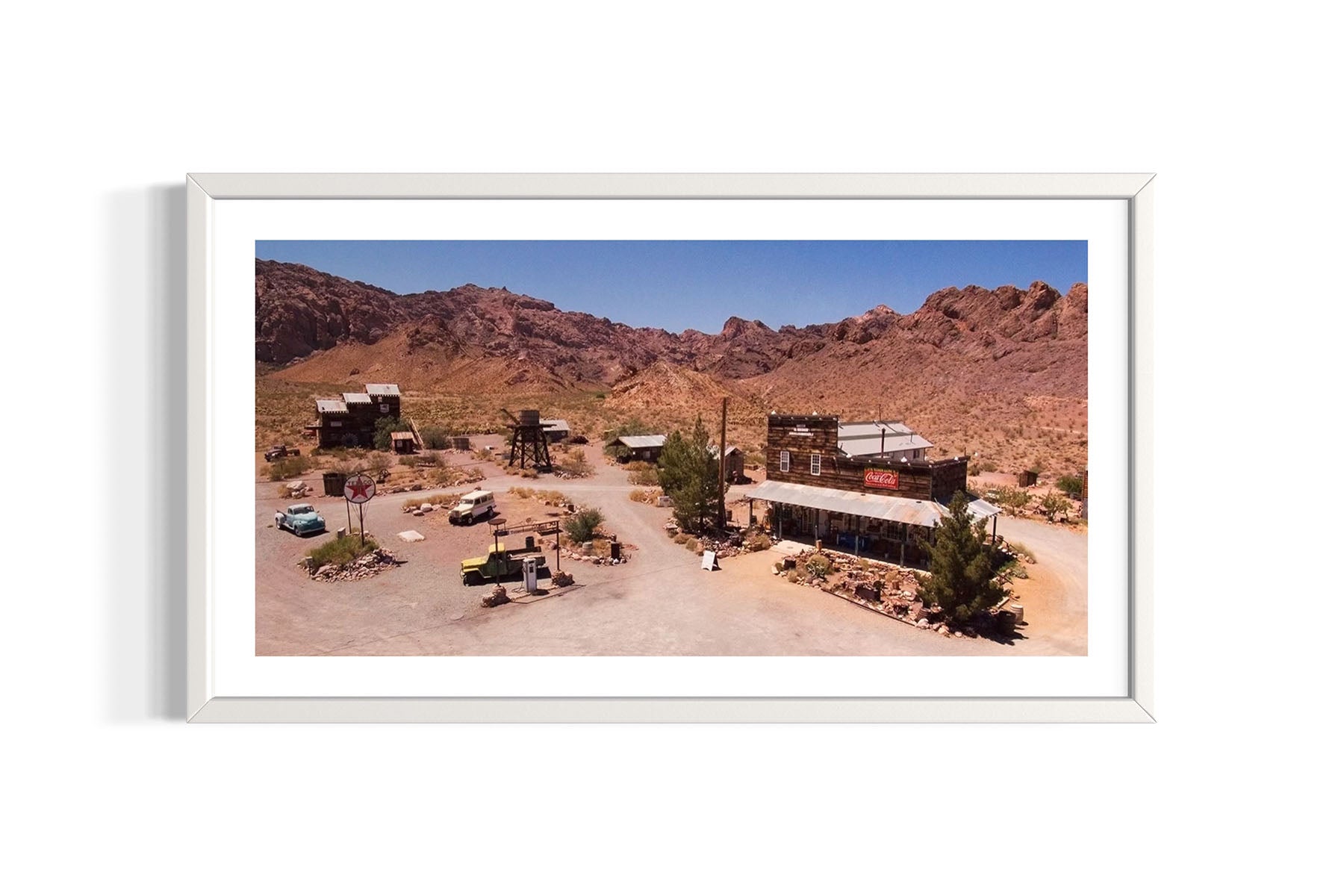 Aerial photograph of a desert landscape with buildings and vehicles in Nelson, Nevada, framed in white by Evan Reinheimer.